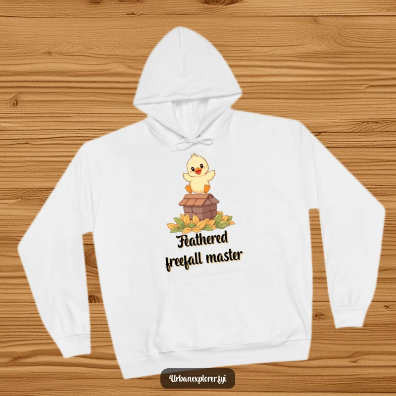 Funny hoodie with a smiling duckling leaping from a rooftop onto leaves, offering warmth and whimsical humor.