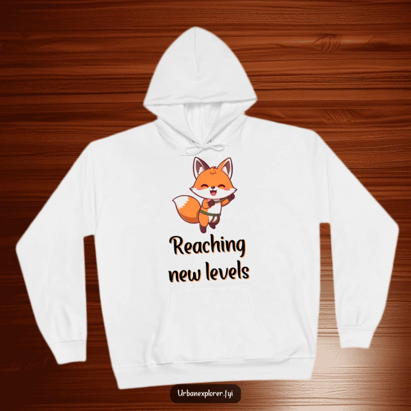 Funny kawaii hoodie with an enthusiastic fox using a grappling hook to ascend a wall, looking determined and playful.